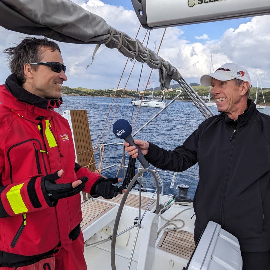 Ein lächelnder Reporter interviewed einen Skipper auf einer Jacht in der Ägäis © NDR Foto: Carsten Vick