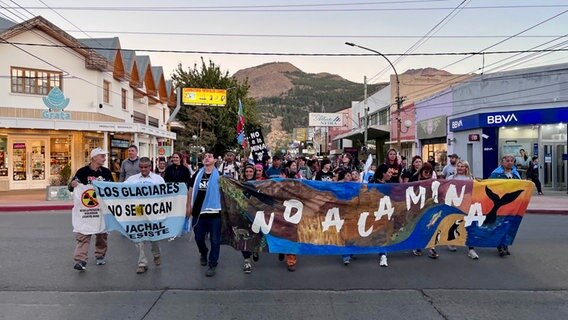 Eine Gruppe von Klima-Aktivisten mit Demo-Fahnen laufen in Argentinien über die Straße, auf den Schildern steht etwa "Fasst die Gletscher nicht an" © NDR Foto: Max-Marian Unger