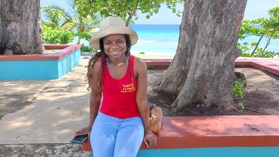 Eine junge Frau mit Hut lächelt auf Barbados in die Kamera © NDR Foto: Isa Hoffinger