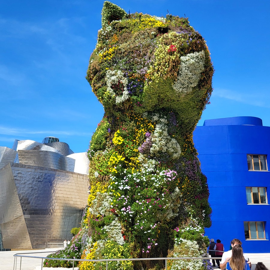 Eine Skulptur so hoch wie ein Gebäude in Form eines Hundes ist von Blumen überwuchert - Eine Hundeskulptur in Bilbao © NDR / Thomas H. A. Becker Foto: Thomas H. A. Becker