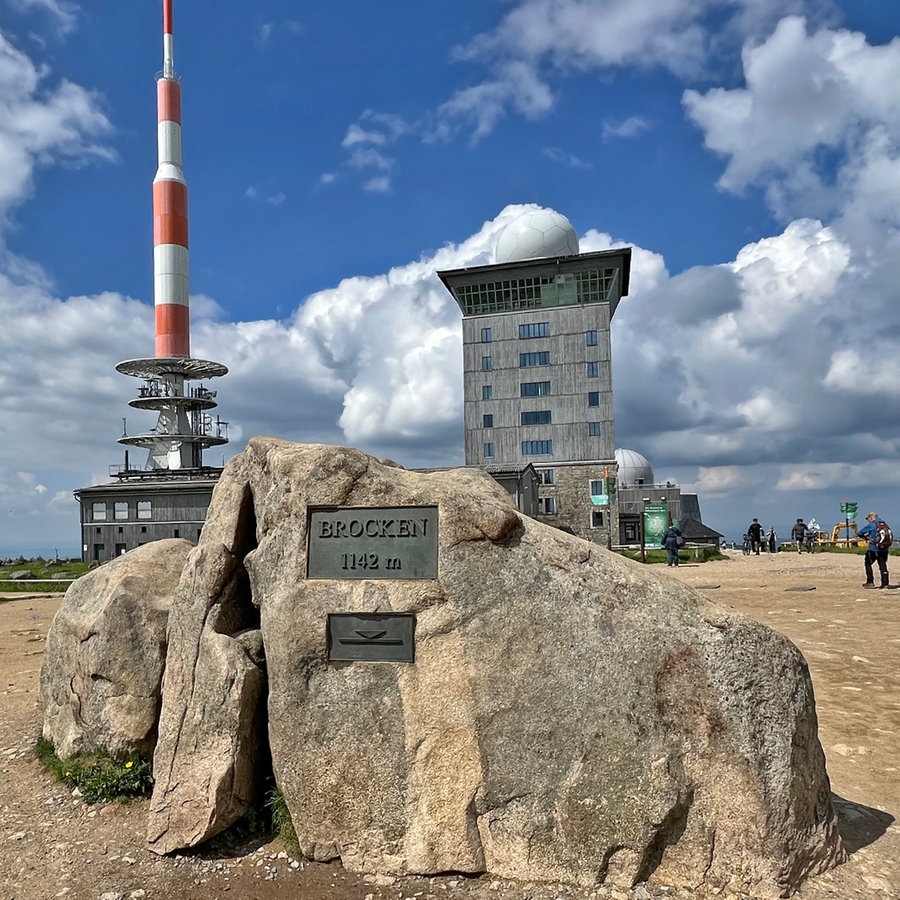 Eine weißrote Antenne, davor ein Felsen, auf dem eine Plakette mit der Inschrift "Brocken" steht, dahinter ein hohes Gebäude © NDR Foto: Carsten Vick