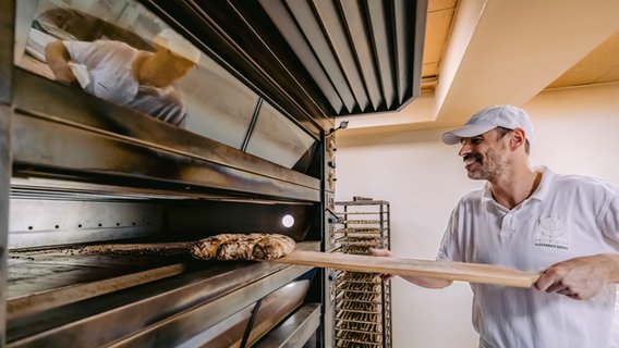 Ein Bäcker in Südtirol holt frisch gebackenes Brot aus dem Ofen © NDR Foto: Alexander Tempel