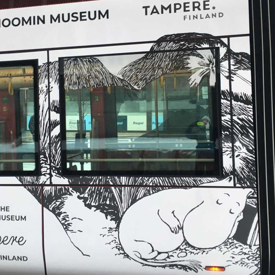 Eine weiße Strahenbahn steht an einer Haltestelle, darauf abgebildet sind schlafende Mumins (Comiczeichnungen mit rundlichen Fabel-Tieren aus Finnland) © NDR Foto: Petra Martin