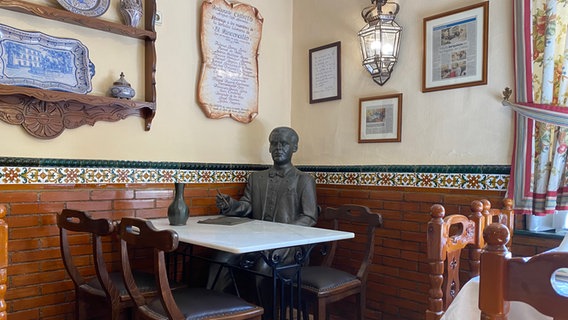 Eine Bronzefigur sitzt in einem traditionallem Restaurant in Granada - die Figur stellt den Dichter Federico García Lorca dar © NDR Foto: Tom Noga