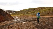 Ein Wanderer läuft auf einem Pfad auf dem isländischen Hochplateau, vorbei an vulkanischem Umfeld © NDR Foto: Merle Schaack und Michael Richmann
