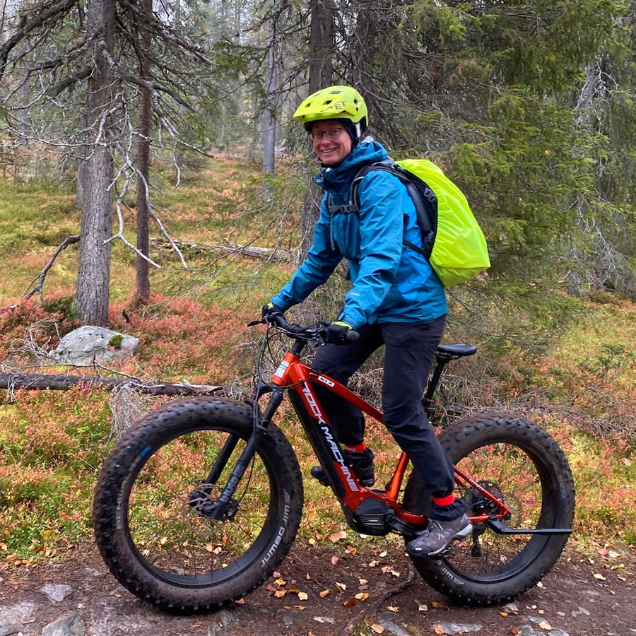 Eine Frau radelt in regenfester, warmer Kleidung durch einen Wald in Lappland © NDR Foto: Petra Martin