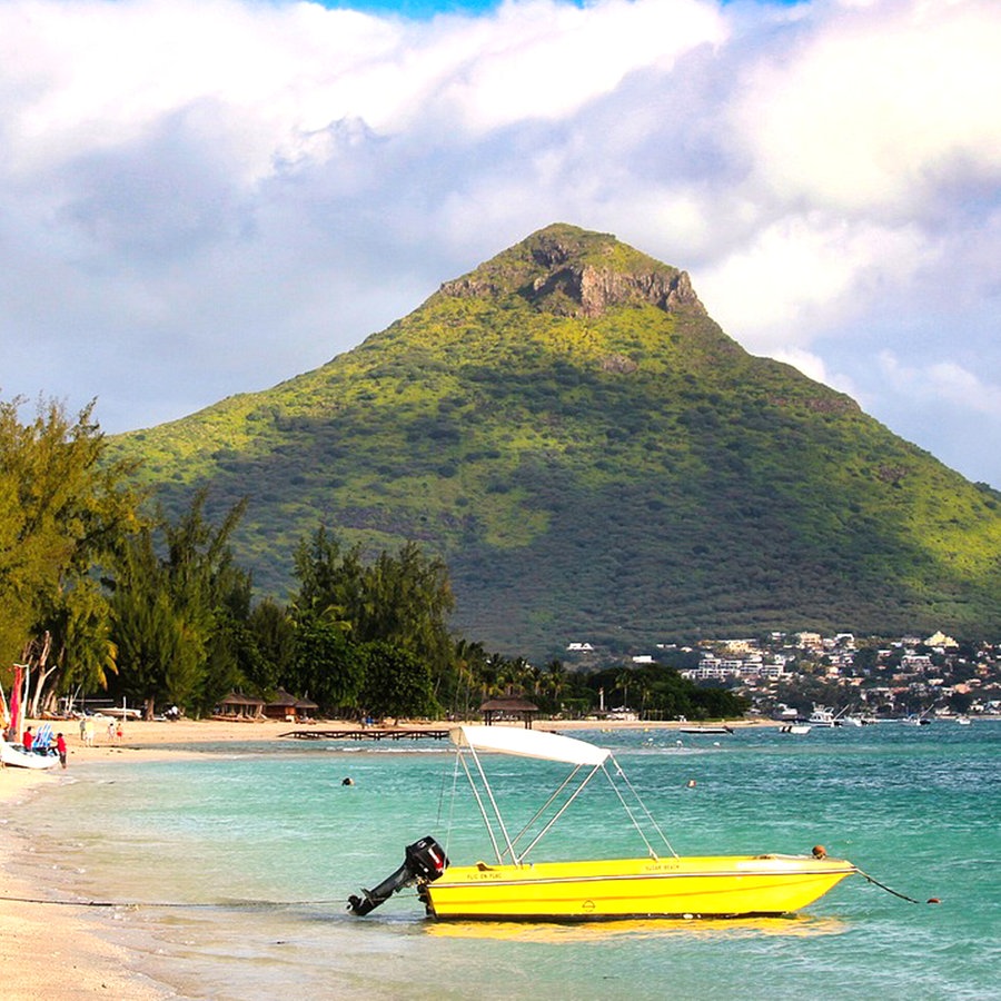 Ein gelbes Boot mit kleinem Außenmotor liegt am Strand von Mauritius, dahinter ist ein Hügel zu erkennen, auch Palmen am weißen Strand © H.Hach  / Pixabay Foto: H.Hach