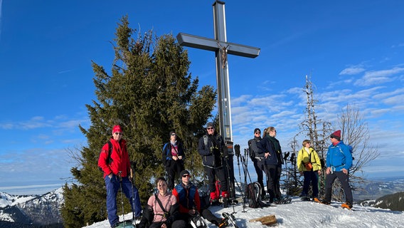 Schneeschuhwanderer machen Rast im Allgäu an einem Kreuz © NDR Foto: Carsten Vick