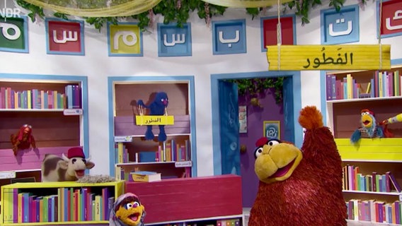 Szene aus einer Sesamstraßenfolge: Winkende Monster in einer Bibliothek (Screenshot).  