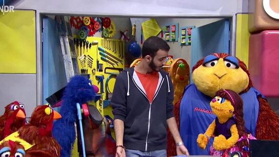 Szene aus einer Sesamstraßenfolge: Eine Gruppe von Monstern in einer Werkstatt (Screenshot).  