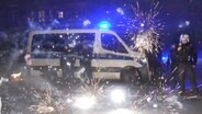 Polizeibeamte stehen in Berlin hinter explodierendem Feuerwerk © Julius-Christian Schreiner/TNN/dpa 