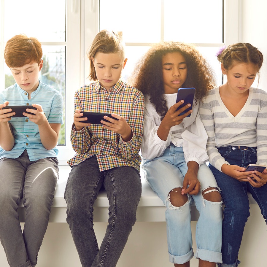 Eine Kindergruppe sitzt auf einer Fensterbank und jeder schaut auf sein Smartphone. © Colourbox Foto: #266241