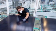 Zwei Mitarbeiter begutachten in der Endkontrolle einer Produktionslinie für Solarmodule im Werk der Meyer Burger Technology AG in Freiberg ein Solarmodul © picture alliance/dpa/dpa-Zentralbild Foto: Hendrik Schmidt