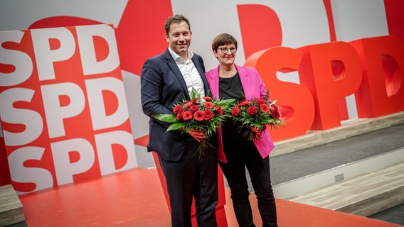 Lars Klingbeil und Saskia Esken stehen beim Bundesparteitag der SPD nach ihrer Wahl zu den Parteivorsitzenden auf dem Podium. Beide halten einen Blumenstrauß in der Hand. © dpa-Bildfunk Foto: Kay Nietfeld