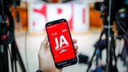 Ein Smartphone, auf dessen Bildschirm in Großbuchstaben "JA" steht © dpa Bildfunk Foto: Kay Nietfeld/dpa