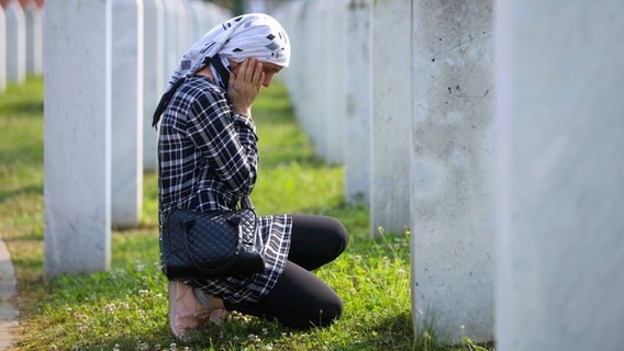 Eine bosnisch-muslimische Frau trauert neben dem Grab eines Verwandten, der dem Völkermord von Srebrenica zum Opfer gefallen war, im Gedenkzentrum in Potocari, Bosnien. © Armin Durgut/AP/dpa 