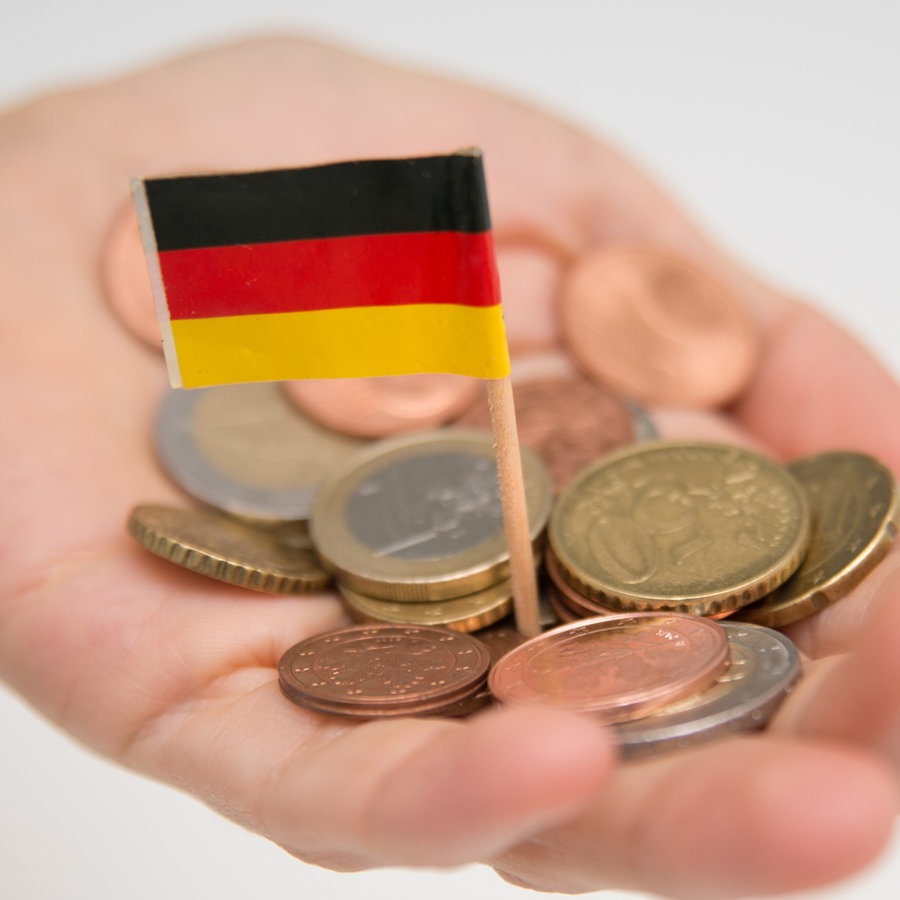 Eine Frau hält Geldstuecke in der Hand, zwischen denen eine kleine Deutschlandfahne steckt. © picture alliance / dpa Themendienst Foto: Andrea Warnecke