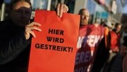 Streikende Angestellte. Ein Mann hält ein Schild hoch mit der Aufschrift: "Hier wird gestreikt!" © picture alliance / ERWIN SCHERIAU / APA / picturedesk.com Foto: ERWIN SCHERIAU