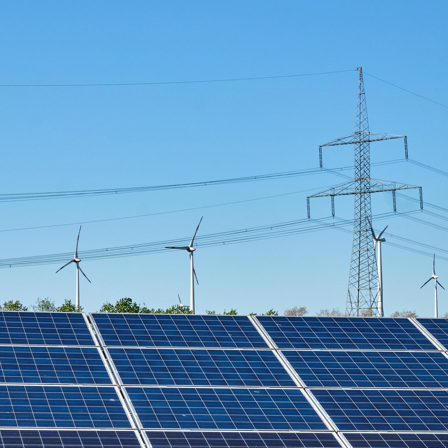 Eine Solaranlage und Windräder im Hintergrund vor blauem Himmel © picture alliance / Shotshop Foto: elxeneize