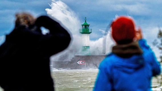 Menschen fotografieren in Sassnitz Wellen der Ostsee, die bei einem schweren Sturmtief an den Leuchtturm auf der Ostmole peitschen. © dpa bildfunk Foto: Georg Moritz