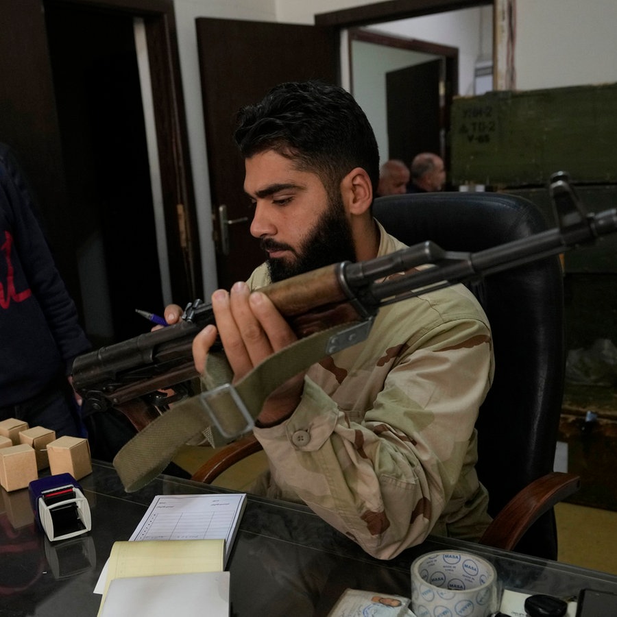 Ein syrischer Kämpfer erhält eine Kalaschnikow von einem Mitglied der Armee des gestürzten syrischen Präsidenten al-Assad im Rahmen des "Identifizierungs- und Versöhnungsprozesses" © AP/dpa Foto: Hussein Malla