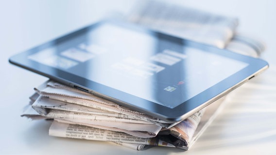 Ein Tablet PC liegt auf einem Zeitungsstapel. © dpa picture alliance 