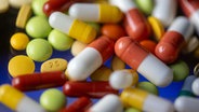 Wild verstreut lieben unterschiedliche, bunte Tabletten und Kapseln auf einem Tisch. © dpa Foto: Hendrik Schmidt