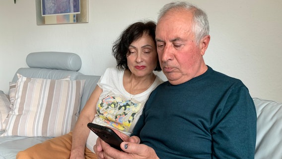 Tanja und Viktor Koktash schauen gemeinsam auf ein Handy. © NDR/privat Foto: NDR/privat