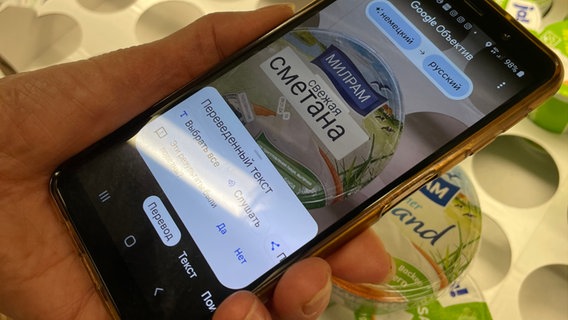 Eine App auf dem Handy von Tanja Koktash übersetzt die Schrift auf den Supermarktprodukten ins Ukrainische. © NDR Foto: Lydia Callies
