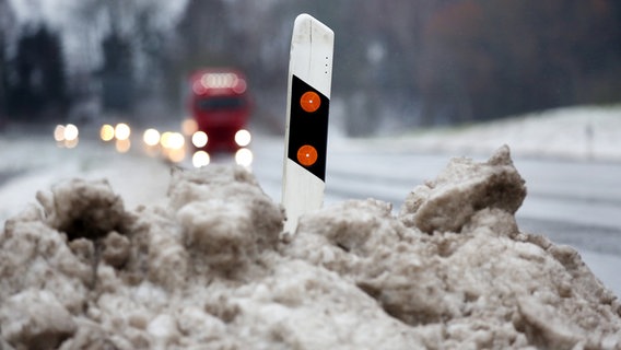 Ein Leitpfosten steht in vom Tauwasser gefärbten Schnee. © fpa Foto: Thomas Warnack