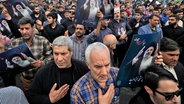 Iran, Teheran: Menschen halten Plakate des iranischen Präsidenten Ebrahim Raisi während einer Trauerfeier für ihn in der Innenstadt von Teheran. © Vahid Salemi/AP/dpa 
