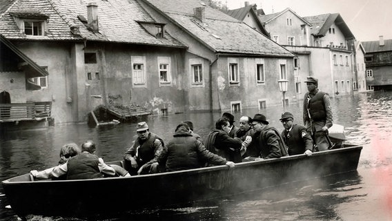 Ein THW-Boot fährt vor überschwemmten Häusern. © THW 