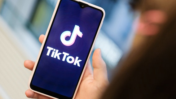 Ein Mädchen hält ihr Smartphone mit dem TikTok Logo in der Hand © dpa Foto: Jens Kalaene