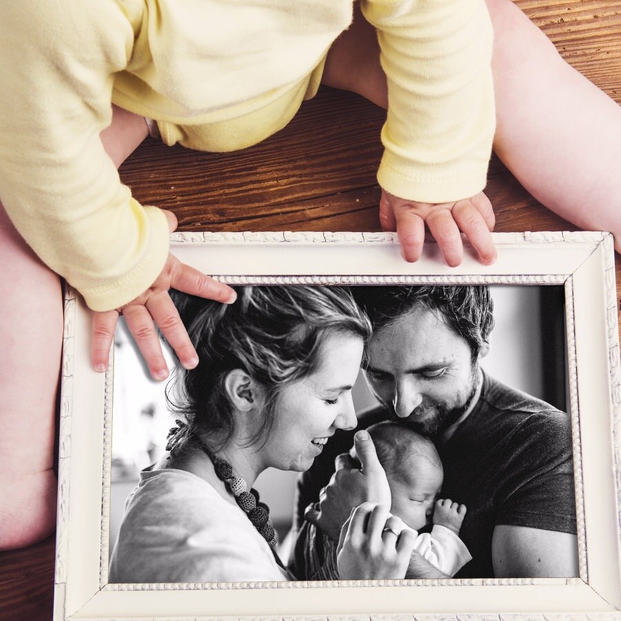 Ein Baby hält ein schwarz-weißes Familienfoto im Rahmen in den Händen © Colourbox Foto: #232319