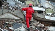 Ein Retter sucht in Kahramanmaras in der Türkei in Trümmern eines Gebäudes nach Überlebenden eines Erdbebens. © dpa bildfunk/XinHua Foto:  Li Zhenbei