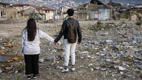 Zwei Geschwister stehen in den Trümmern der Altstadt von Antakya (Türkei). Beide waren bei einem Erdbeben vor einem Jahr verschüttet worden. © Boris Roessler/dpa 
