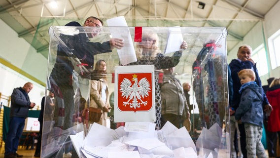 Polnische Bürger stecken ihre Wahlzettel anlässlich der Parlamentswahlen in eine gläserne Wahlurne © picture alliance / ZUMAPRESS.com Foto: Beata Zawrzel