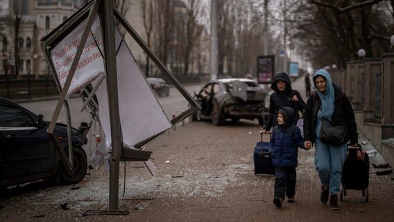 Flüchtende Frauen gehen mit einem Jungen zum Bahnhof von Kiew, um zu versuchen, die Stadt zu verlassen. © picture alliance/dpa/AP | Emilio Morenatti 