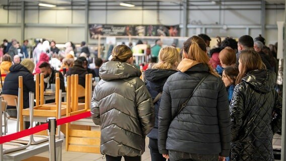 Menschen stehen in einer Kantine einer Erstaufnahmestelle für Flüchtlinge in einer Warteschlange. © dpa bildfunk Foto: Stefan Puchner