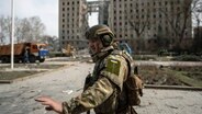 Ein ukrainischer Soldat steht bei einem zerstörten Gebäude in der Stadt Mykolajiw. © dpa Bildfunk/AP Foto: Petros Giannakouris