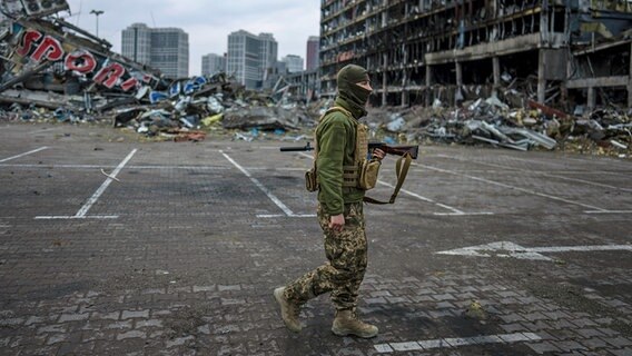 A Ukrainian soldier walks down a street in Kiev past the rubble of a building.  © dpa Bildfunk / AP Photo: Rodrigo Abd