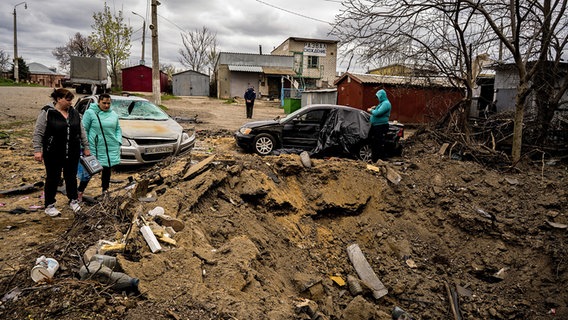 Zwei Frauen betrachten den Krater, den eine Rakete in einem Wohnviertel in Mykolajiw in der Ukraine hinterlassen hat. © dpa Bildfunk/ZUMA Press Wire Foto: Vincenzo Circosta