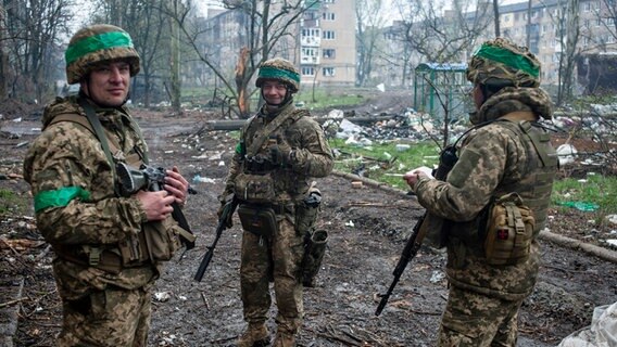 Ukrainische Soldaten unterhalten sich auf der Straße in der vom Krieg betroffenen Stadt Bachmut. © Iryna Rubakova/AP 
