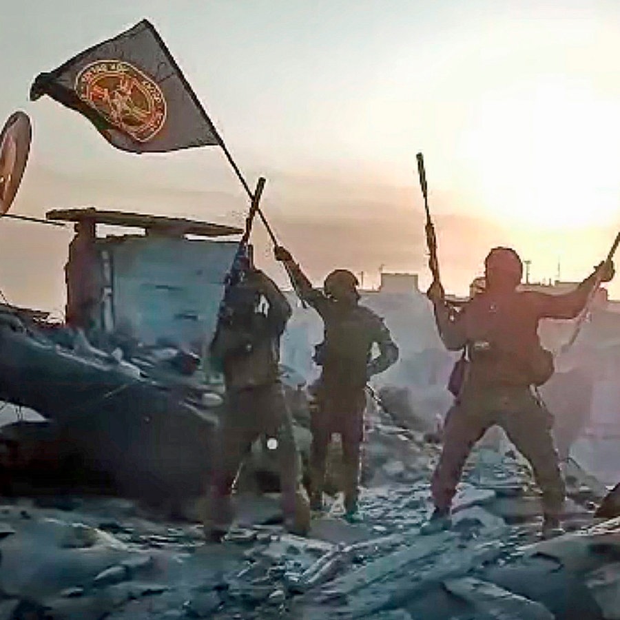 Ein Video-Standbild soll zeigen, wie Soldaten eine russische National- und eine Wagner-Flagge auf einem beschädigten Gebäude in der ukrainischen Stadt Bachmut schwenken. © dpa picture alliance / Zoonar Foto: Leonid Altman