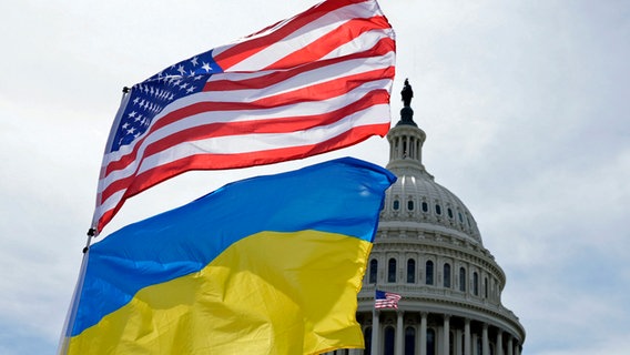 Die US-amerikanische und die ukrainische Flagge wehen vor dem Kapitol in Washington im Wind. © Mariam Zuhaib/AP/dpa 