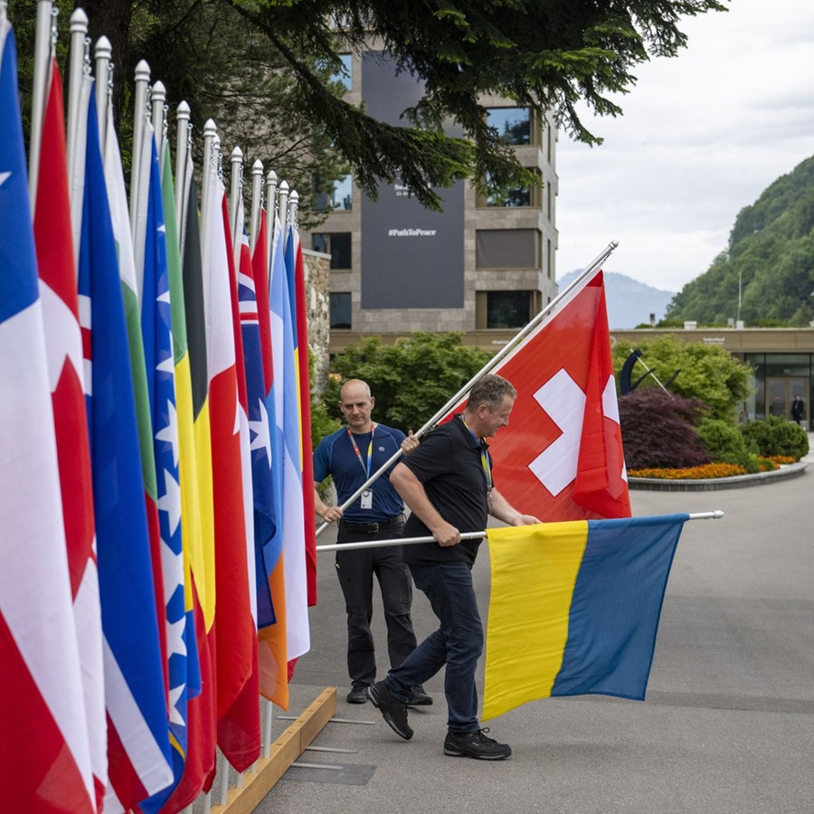 Ein Mann platziert die Flagge der Schweiz während der letzten Vorbereitungen für den Ukraine-Friedensgipfel. © picture alliance/dpa/KEYSTONE/EDA/POOL | Foto:  Urs Flueeler