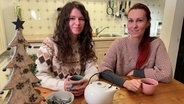 Auf dem Bild sind die beiden jungen Ukrainerinnen Olga und Katya zu sehen. Sie trinken Tee in der Küche von ihrem Vermieter. © NDR Foto: Anina Pommerenke
