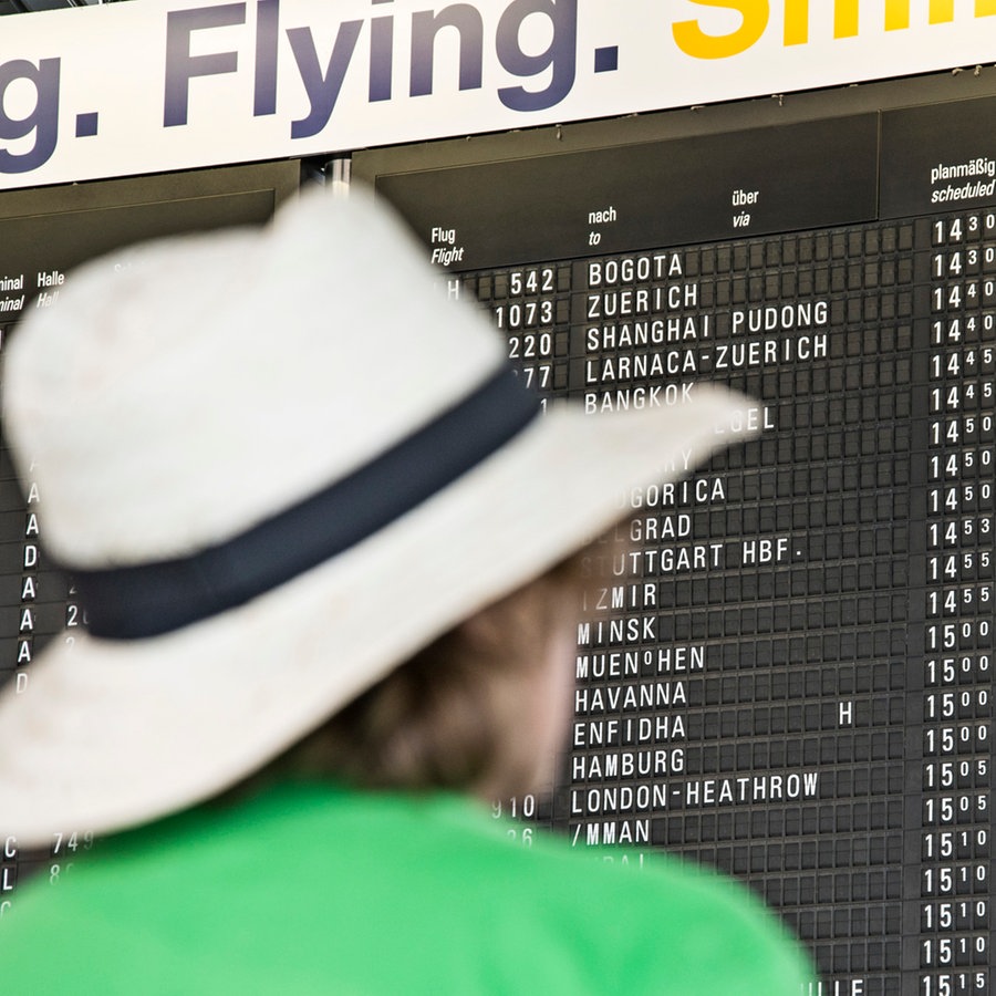 Ein Mann mit Hut schaut auf eine Anzeigentafel in einem Flughafen © picture alliance Foto: Klaus Ohlenschläger