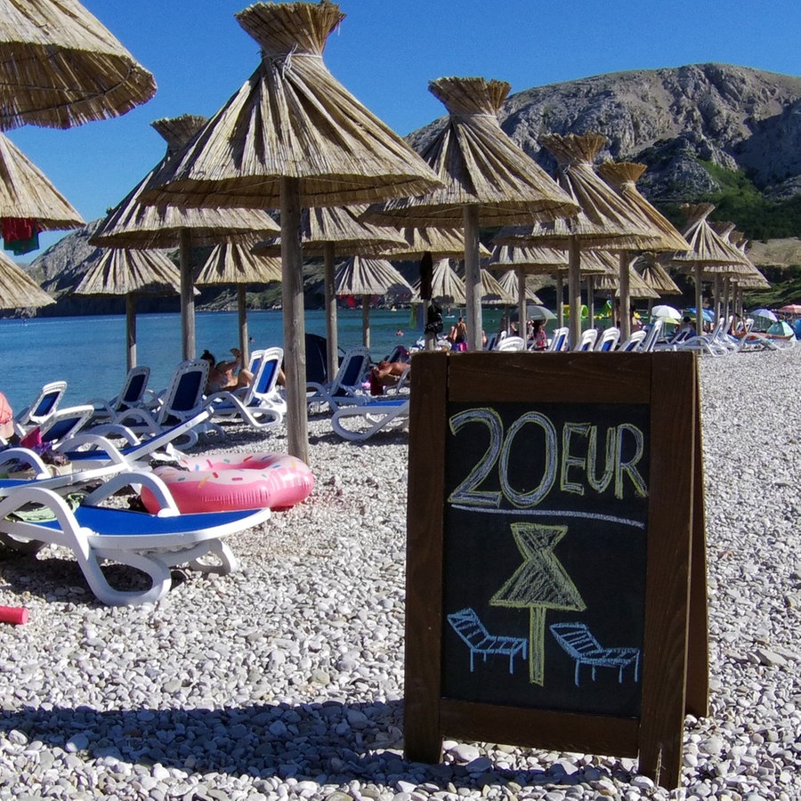Strandszene mit Sonnnschirmen und Strandliegen in Kroatien mit einem Aufsteller: "20 Euro pro Liegestuhl" © picture alliance / johapress Foto: Joachim Hahne