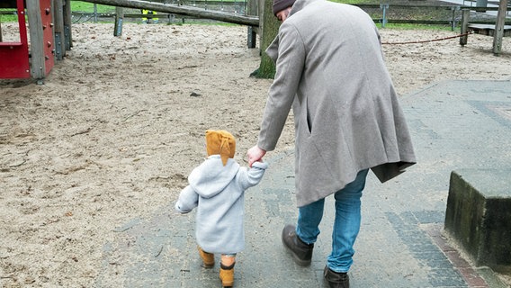 Ein Vater hält sein Kleinkind beim Gehen an der Hand. © picture alliance Foto: Marco Rauch